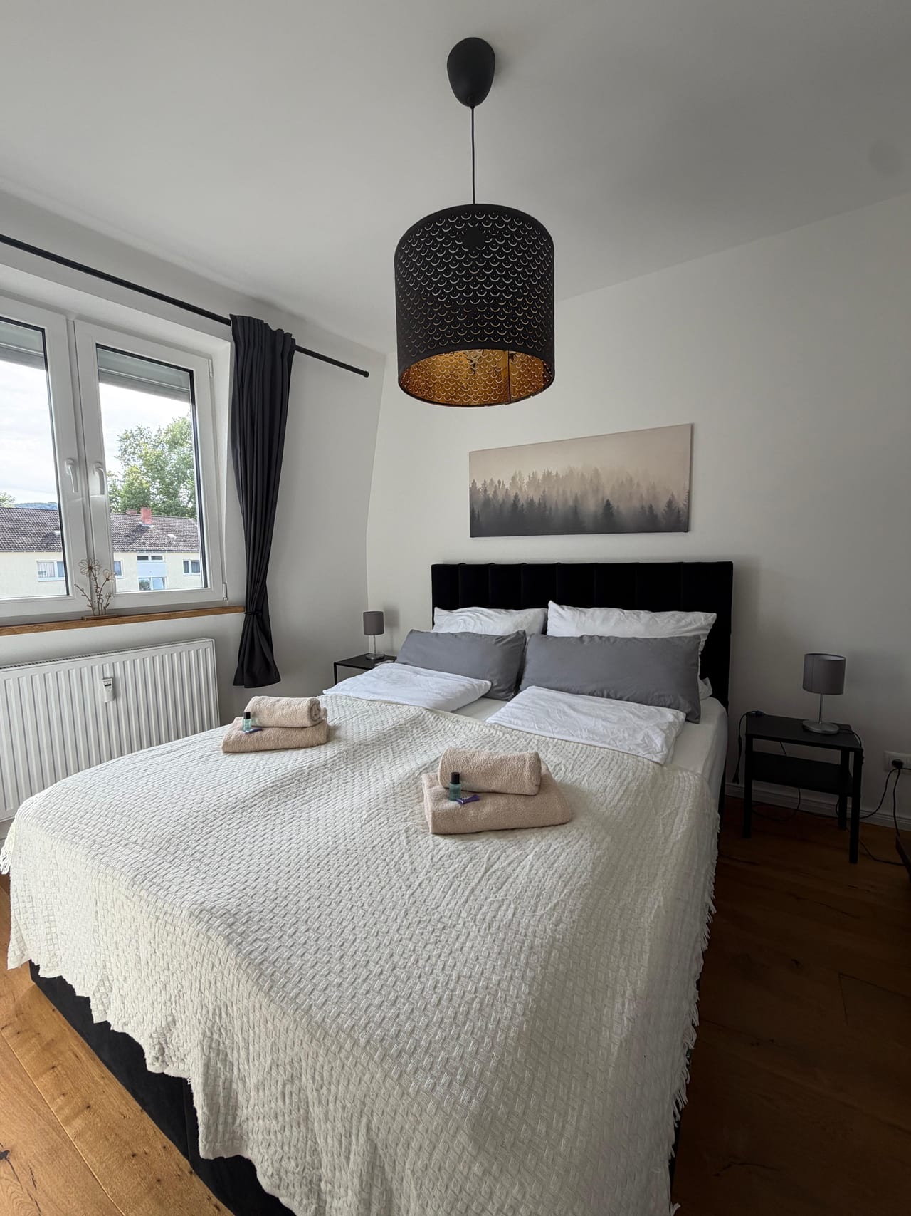 Schlafzimmer mit Doppelbett, frischer Bettwäsche und bereitgelegten Handtüchern
