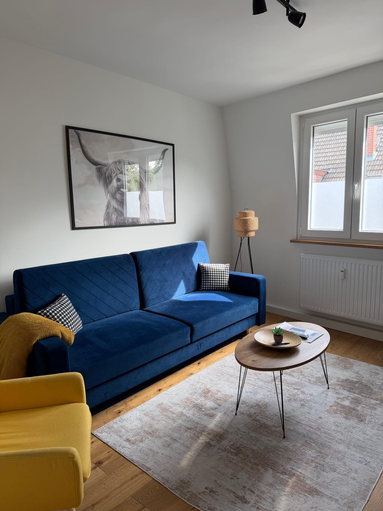Heller Wohnbereich mit blauem Sofa, gelbem Sessel und Couchtisch
